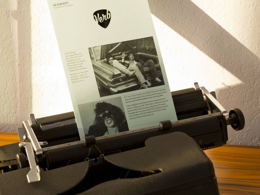 A vintage typewriter with a sheet of paper inserted, displaying text and a photograph.