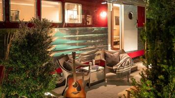 A cozy outdoor seating area with a guitar, a cushioned chair, and a small table.