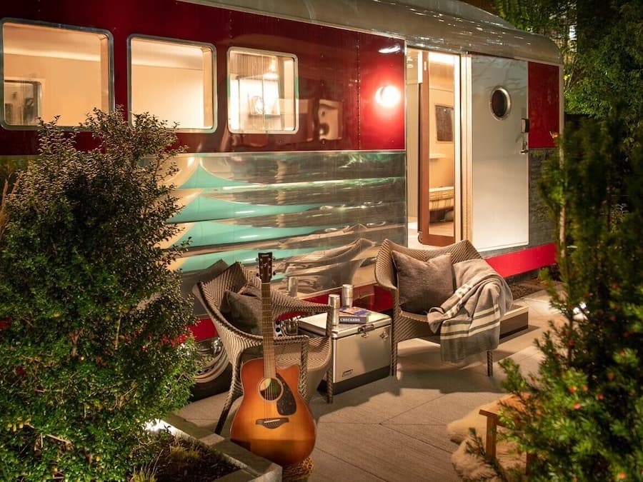 A cozy outdoor seating area with a guitar, a cushioned chair, and a small table.