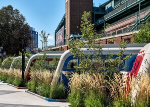 Une gare moderne, avec un ciel dégagé, un bâtiment en briques et une enseigne sur laquelle on peut lire : « BIENVENUE À KENYON ».