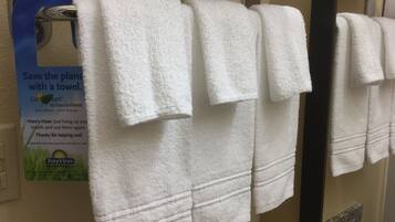 Une rangée de serviettes blanches est suspendue à un porte-serviettes dans une salle de bain.