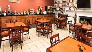 Un comedor con mesas y sillas de madera, una cocina con armarios y electrodomésticos, y una chimenea.