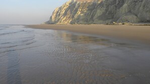 Una playa con un gran acantilado y cielo despejado.