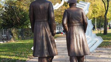 Una estatua de dos figuras vestidas con traje tradicional caminando por un sendero.