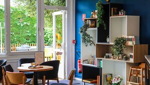 Una habitación acogedora con una mesa redonda, sillas, una estantería y vistas al exterior.