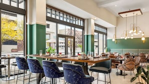 Un restaurante con techos altos, ventanas amplias y una combinación de mesas de bar y comedor.
