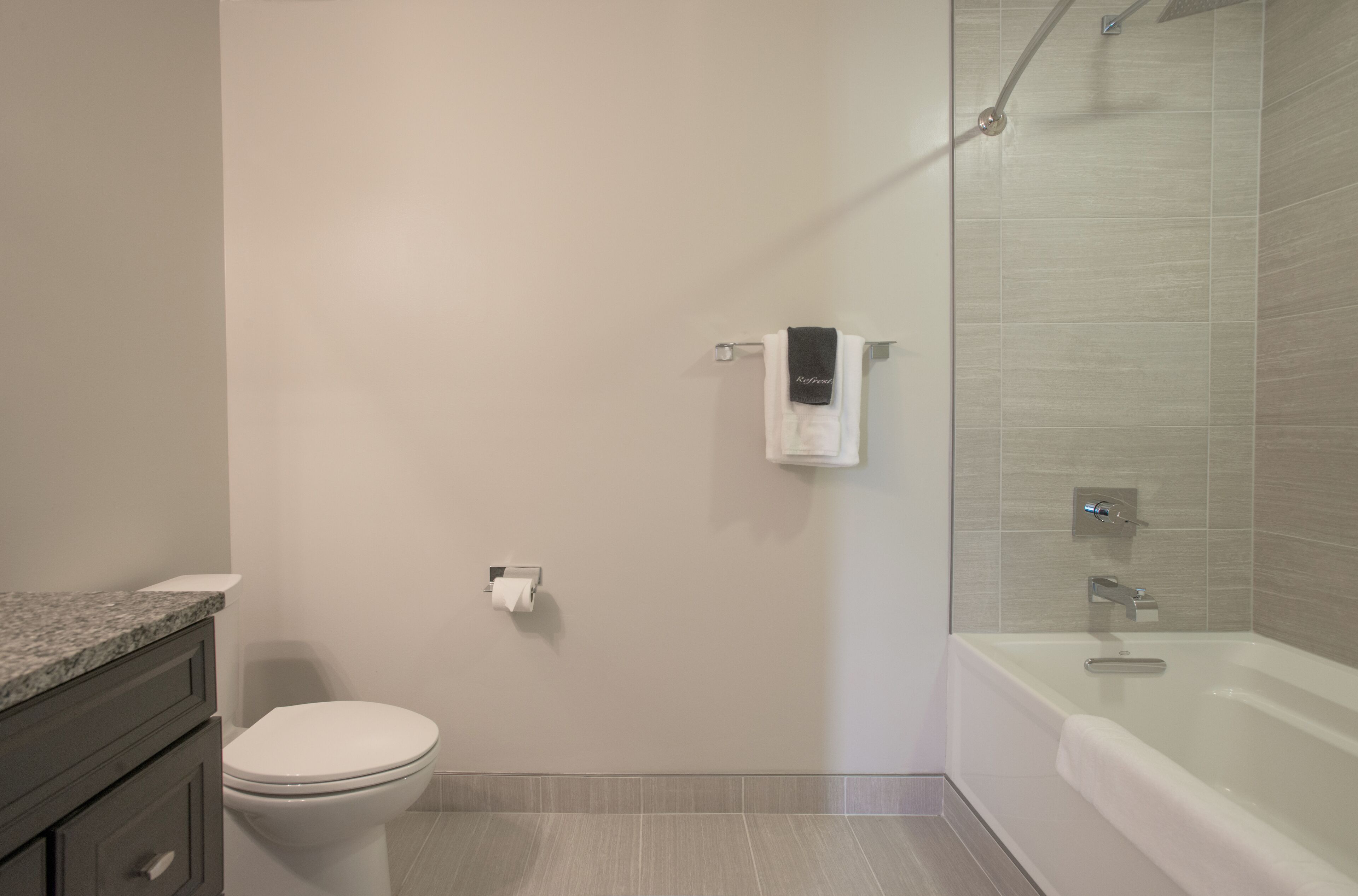 A modern bathroom with a toilet, a towel rack, and a shower area.