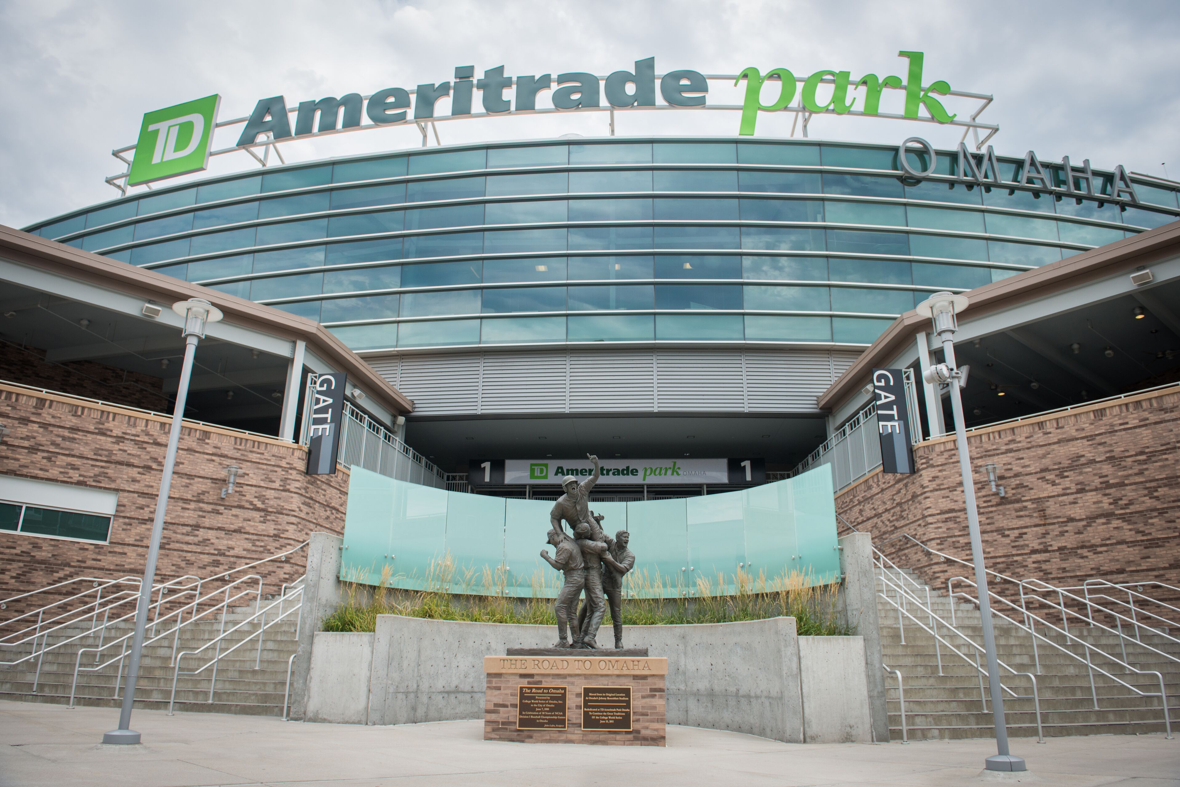 The exterior of Ameritrade Park with a large glass facade, a statue in front, and a sign above the entrance.