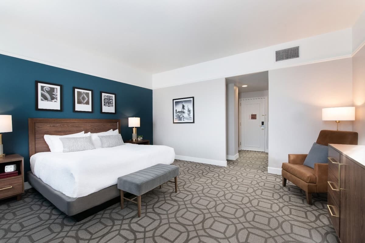 A hotel room with a large bed, bedside tables, a desk, and a chair.