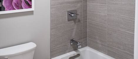 A modern bathroom with a toilet, a shower, and a bathtub.