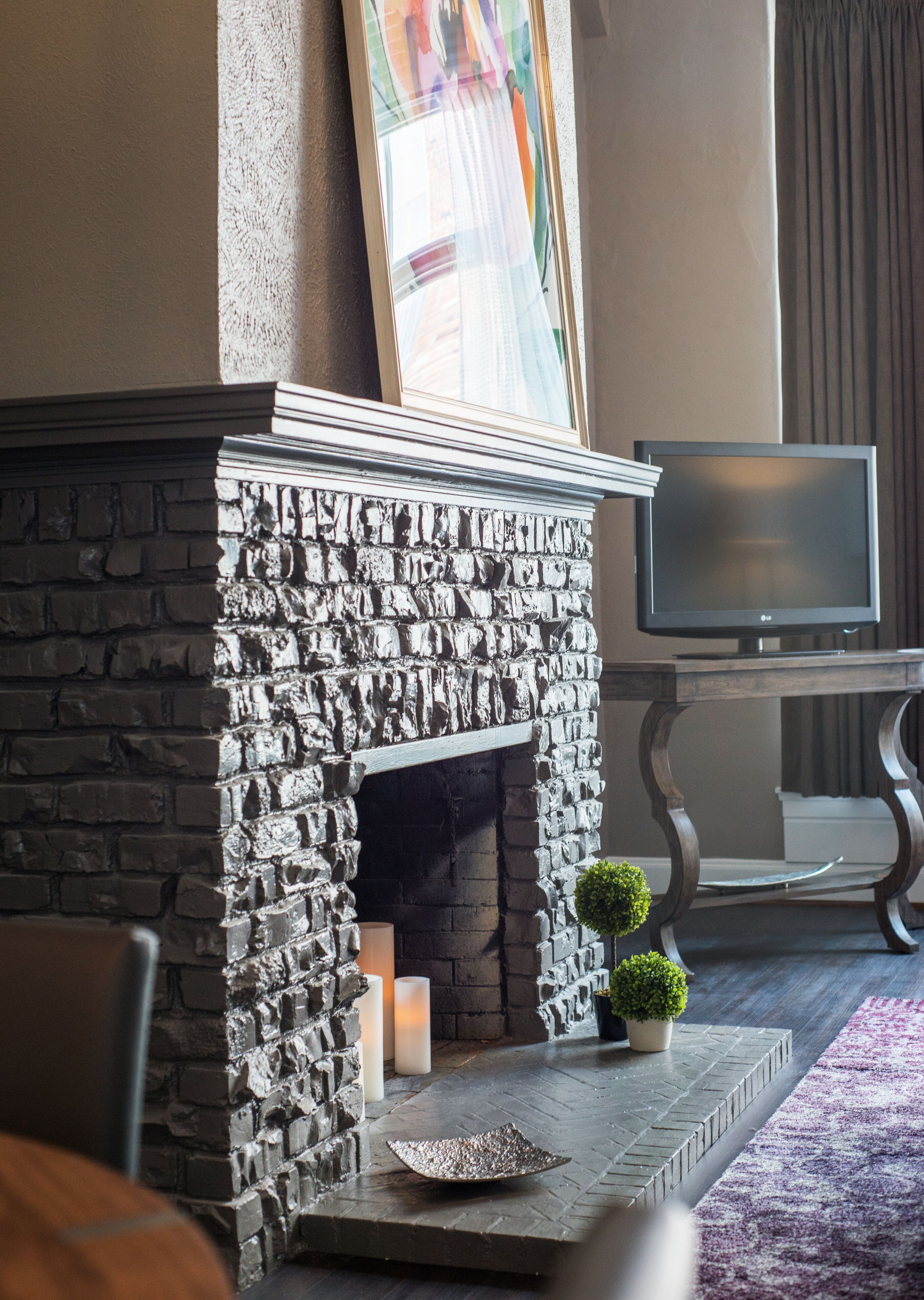 A stone fireplace with a television on a stand to the right.