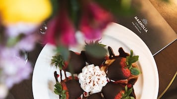 Un plato de postre con fresas bañadas en chocolate, crema batida y salsa de chocolate sobre un plato blanco.