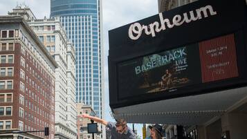 A city street with a large digital billboard advertising a theater.