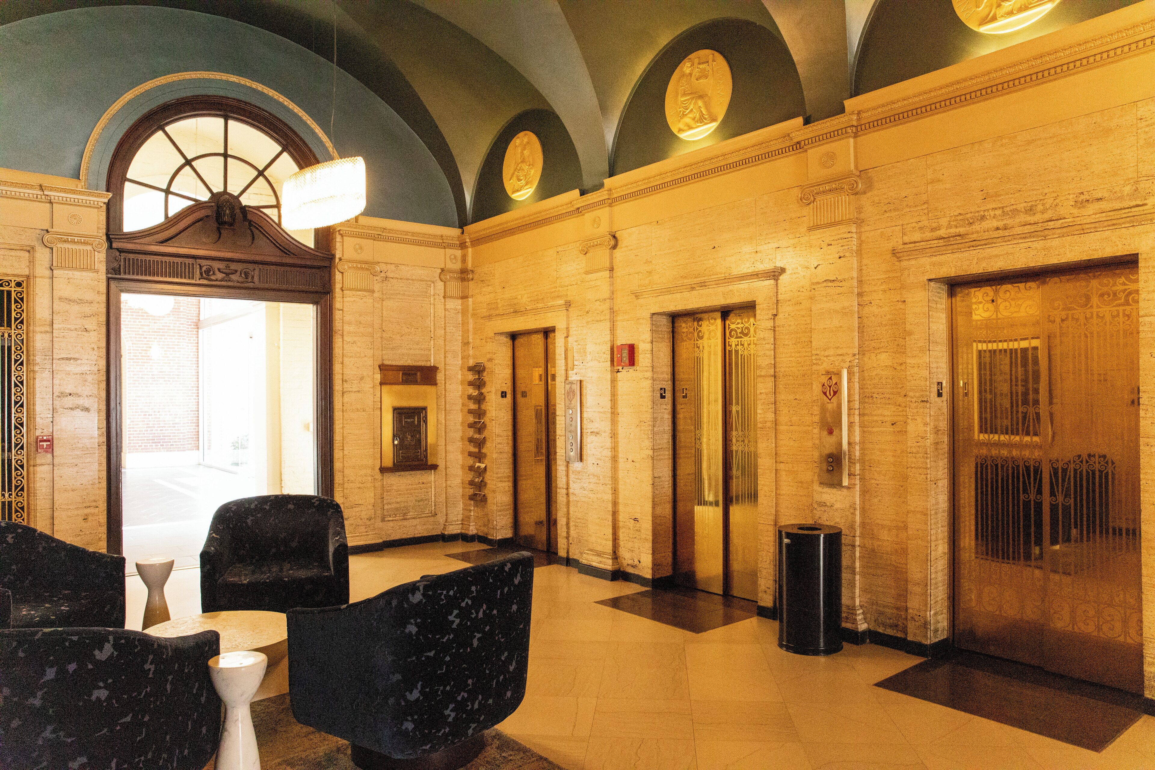 A lobby with marble walls, a chandelier, and a reception desk.