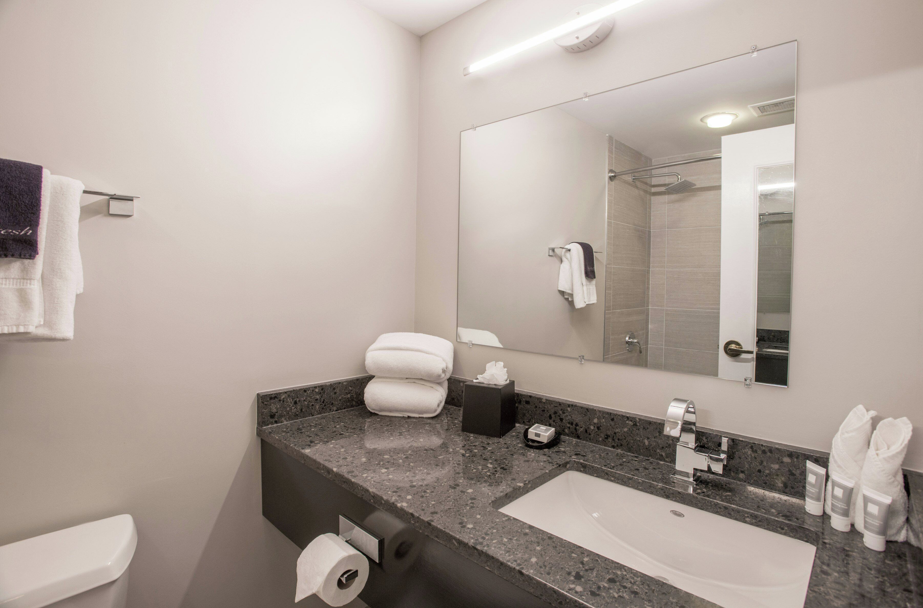 A modern bathroom with a large mirror, a sink, and a toilet.