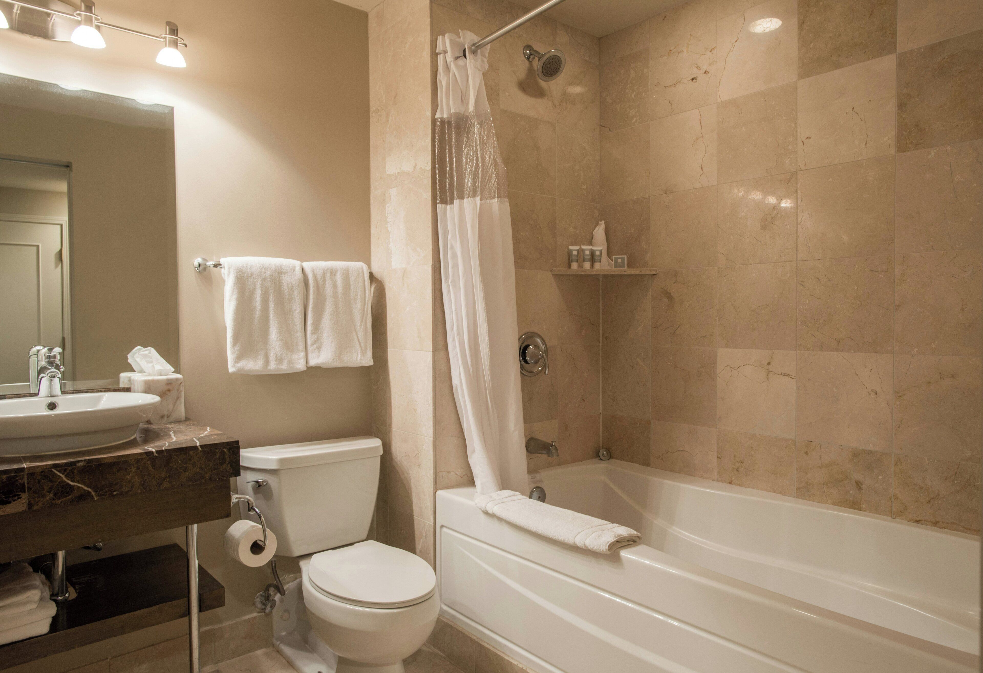 Une salle de bain équipée d’une baignoire, de toilettes, d’un lavabo et d’une douche avec un rideau.