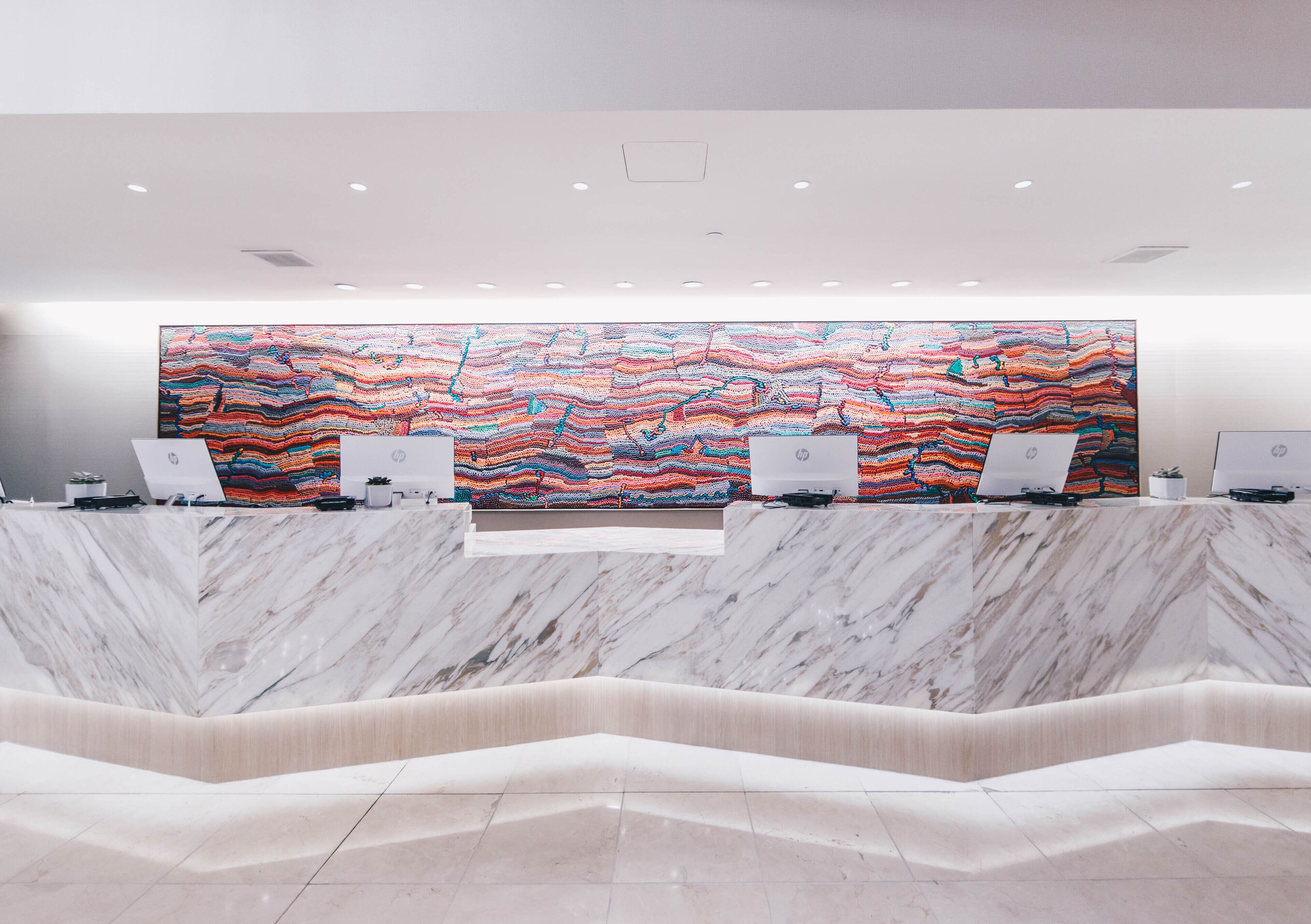 A reception area with a marble counter, multiple computer stations, and a colorful abstract mural on the wall.