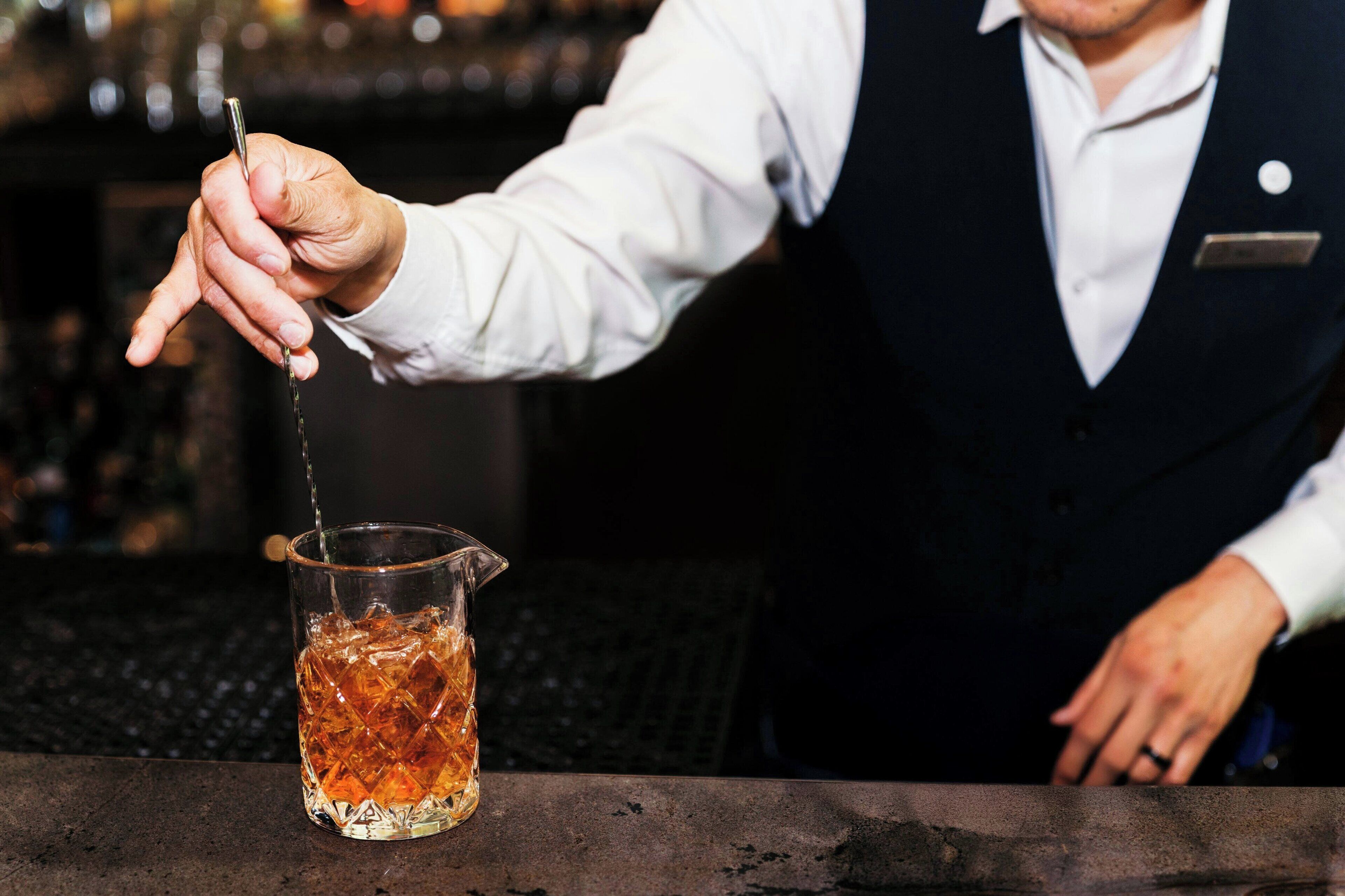 A bartender pouring a drink into a glass.