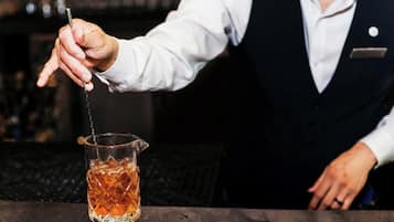 A bartender pouring a drink into a glass.