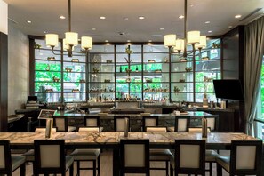 A bar area with marble tables, cushioned chairs, and a variety of bottles and glasses. - Sheraton Grand Seattle (Seattle)