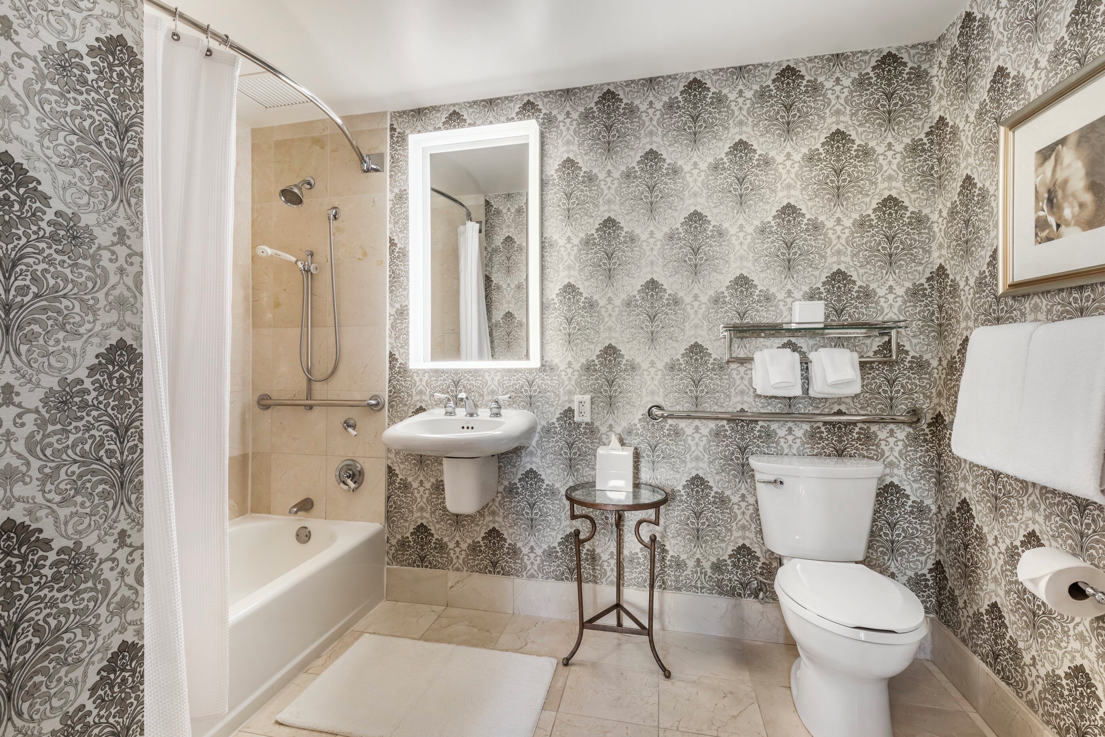 A bathroom with a bathtub, a sink, a toilet, and a mirror.