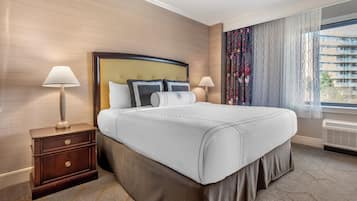 Habitación de hotel con una cama grande, dos mesitas de noche con lámparas, una ventana con cortinas y vistas a edificios.