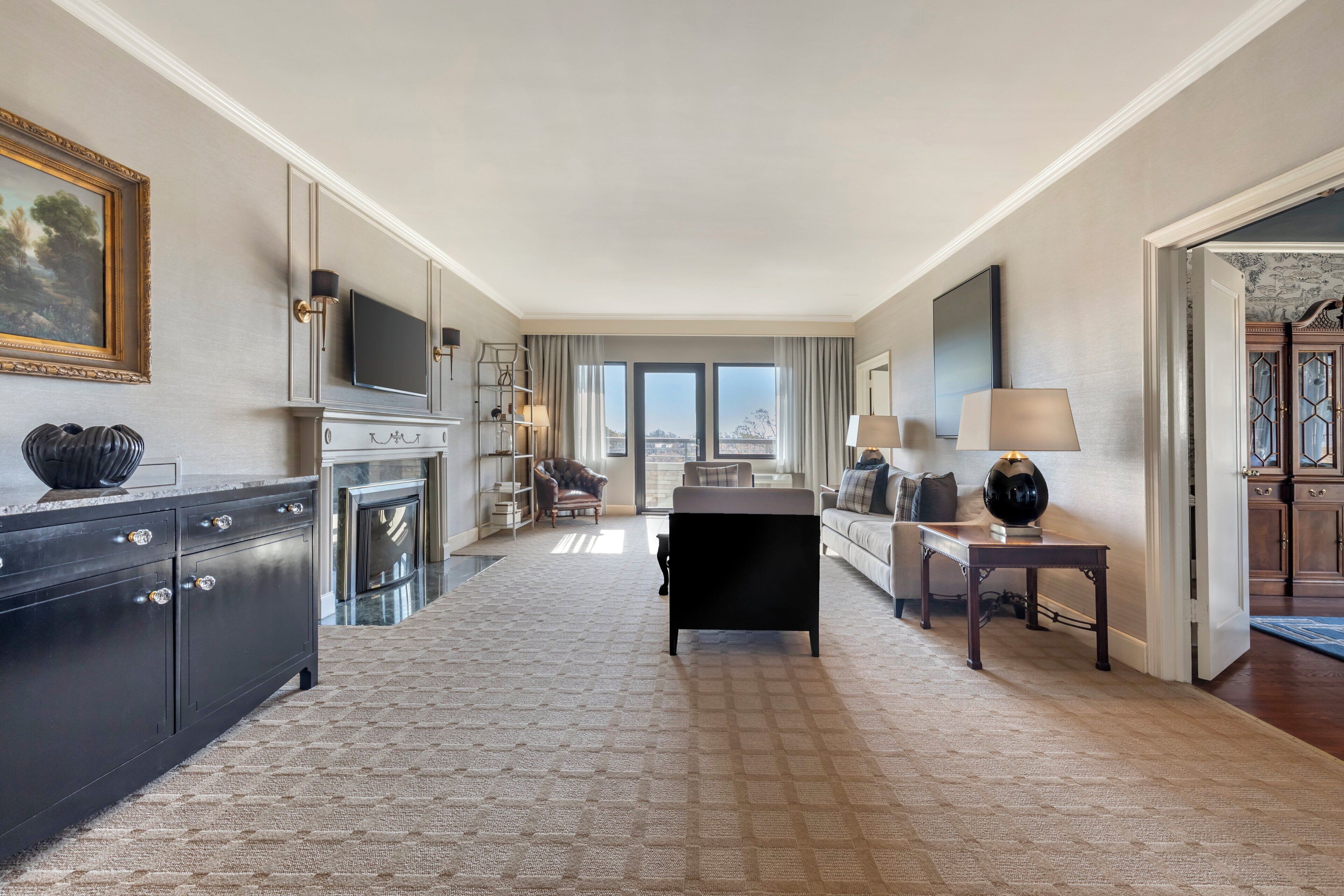 A hotel room with a large bed, a desk, a chair, a TV, and a view of the city.