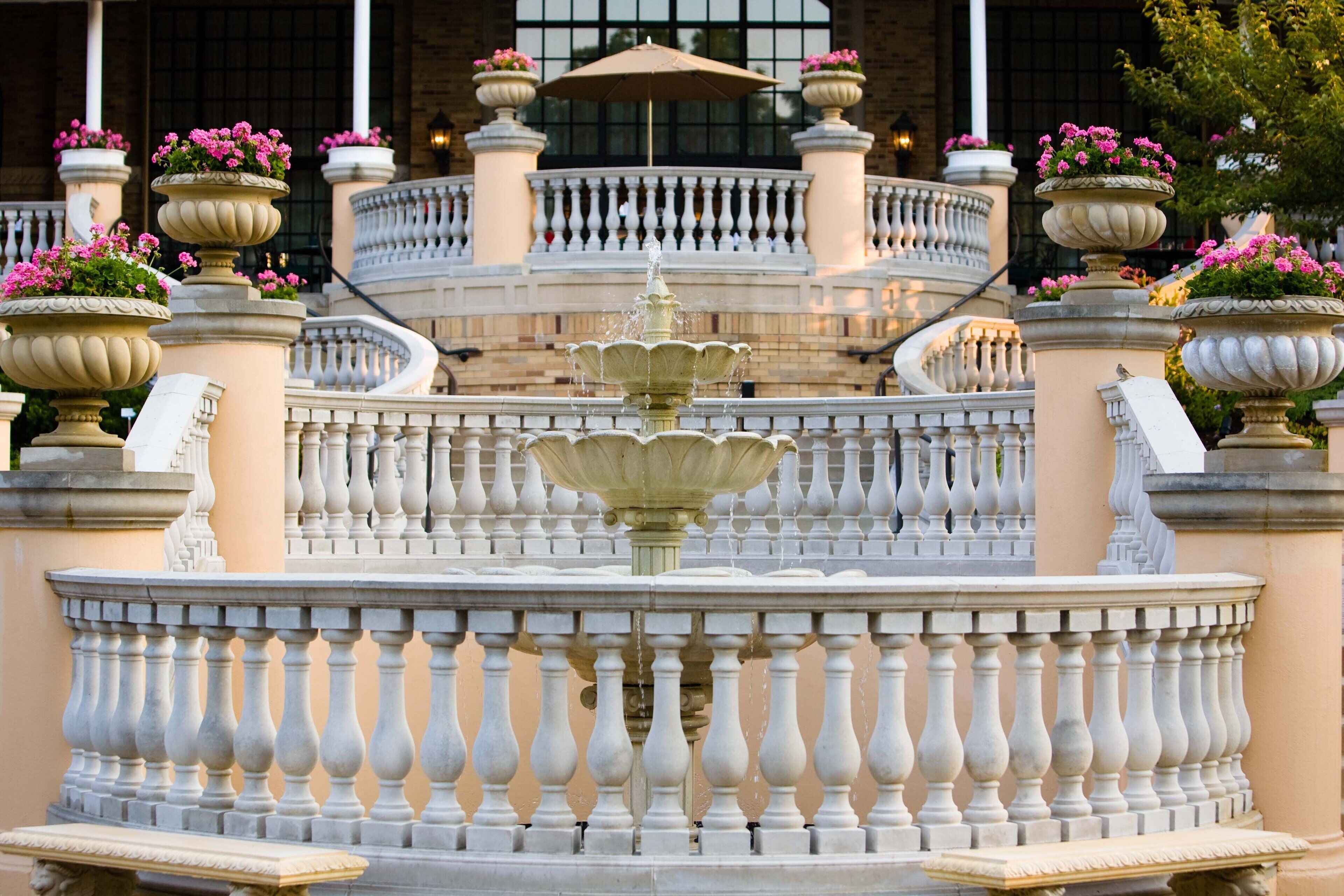 Un'imponente fontana circondata da elaborate ringhiere e vasi di piante.