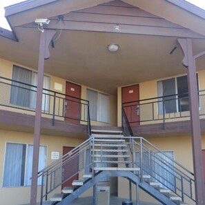 Un edificio de varios pisos con una escalera central, balcones y un área cubierta.