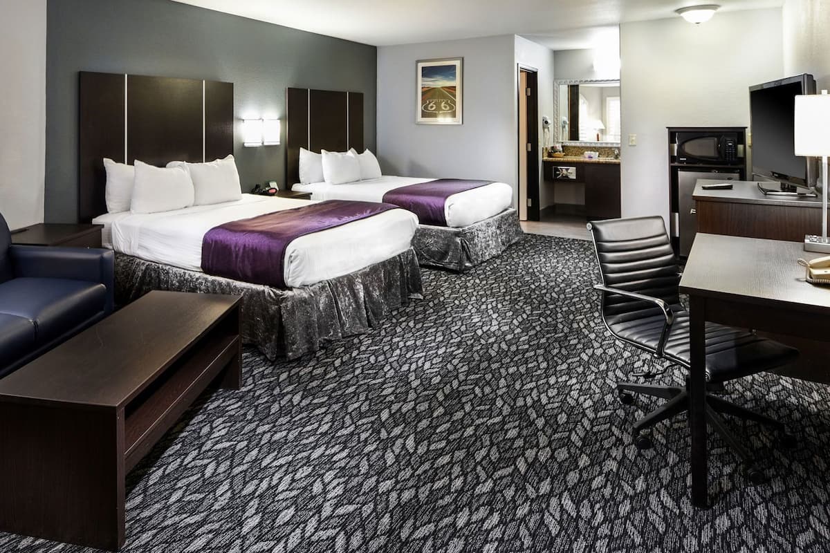 A hotel room with two beds, a sofa, a desk, and a chair.