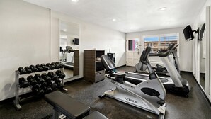 A gym with treadmills, an elliptical, dumbbells, a bench, and a mirror. - Best Western Desert Villa Inn (Barstow)