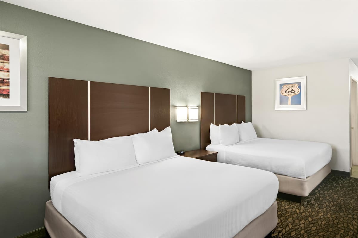 Ein Hotelzimmer mit zwei Betten, einem großen Spiegel und einem gerahmten Bild von Route 66 an der Wand.