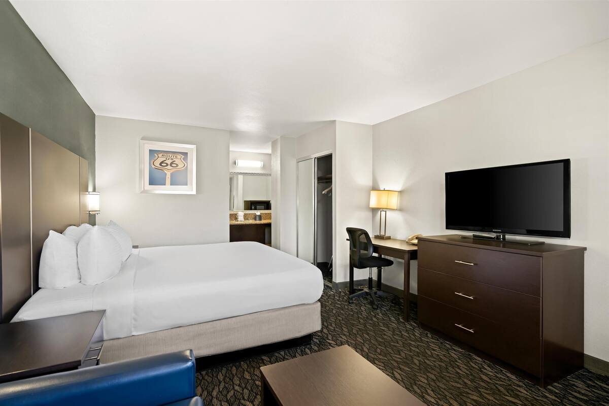 Ein Hotelzimmer mit Bett, Schreibtisch, Fernseher und einem durch eine geöffnete Tür einsehbarer Badezimmer.