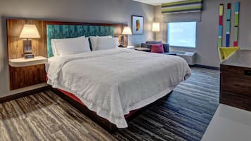 Habitación de hotel con una cama grande, dos mesitas de noche con lámparas, una ventana con vistas y un diseño moderno en la pared.