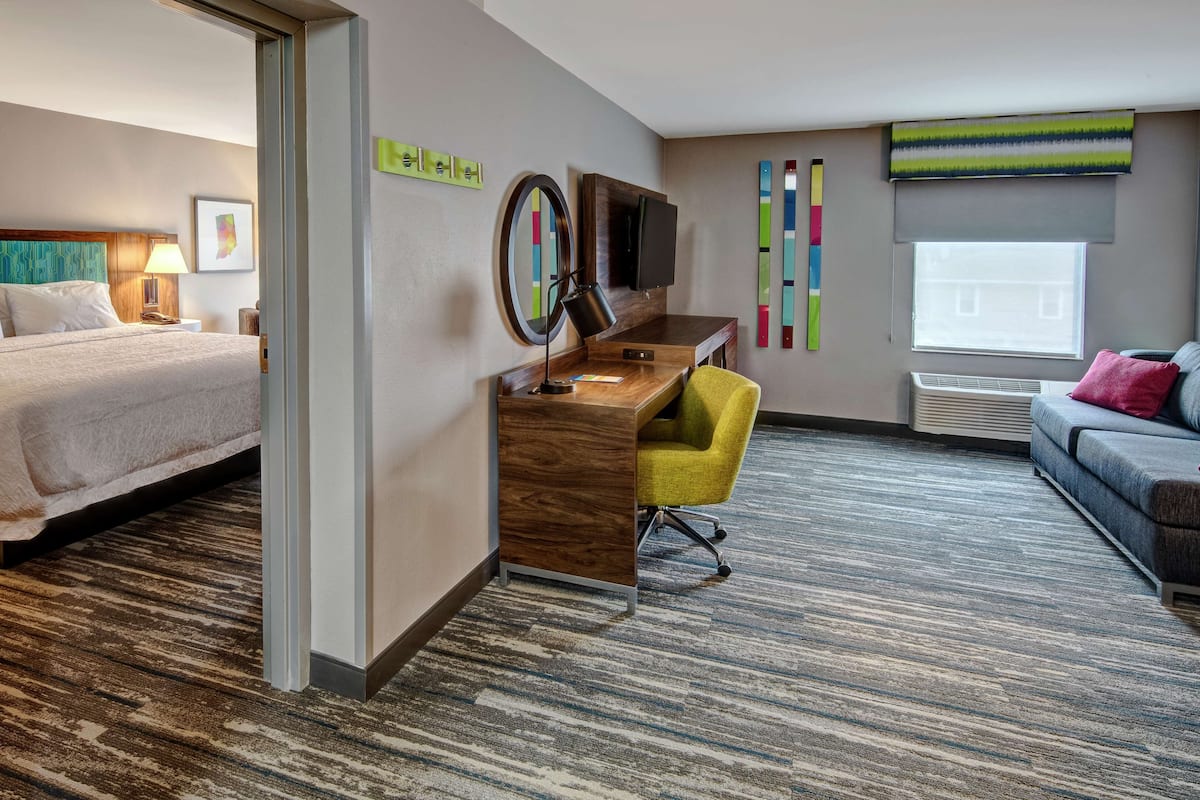 Habitación de hotel con cama, escritorio, silla, televisor y ventana.