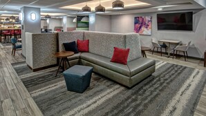 Un vestíbul d'hotel modern amb un sofà modular, una taula petita i una zona de bar al fons.