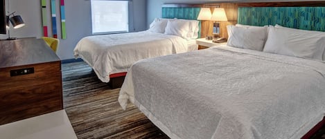 Une chambre d’hôtel avec deux lits, un bureau, une chaise, une lampe et une fenêtre.