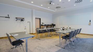 Ein Konferenzraum mit einem großen Tisch, Stühlen, einem Projektor und einer Whiteboard-Tafel.