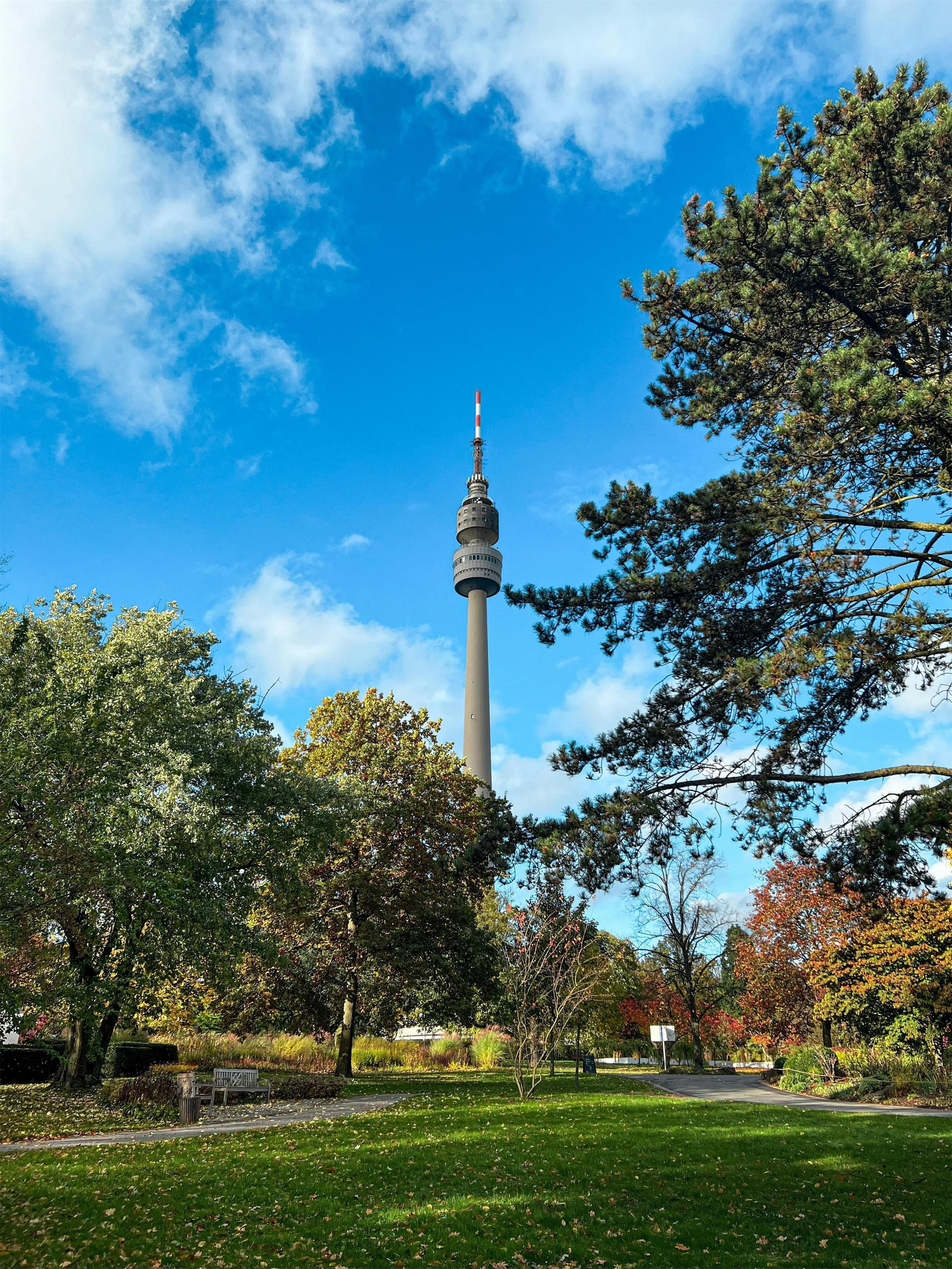 A park with a tall tower, benches, and trees.