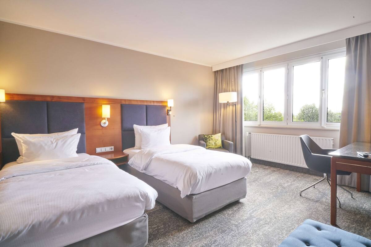 A hotel room with two beds, a desk, and a chair.