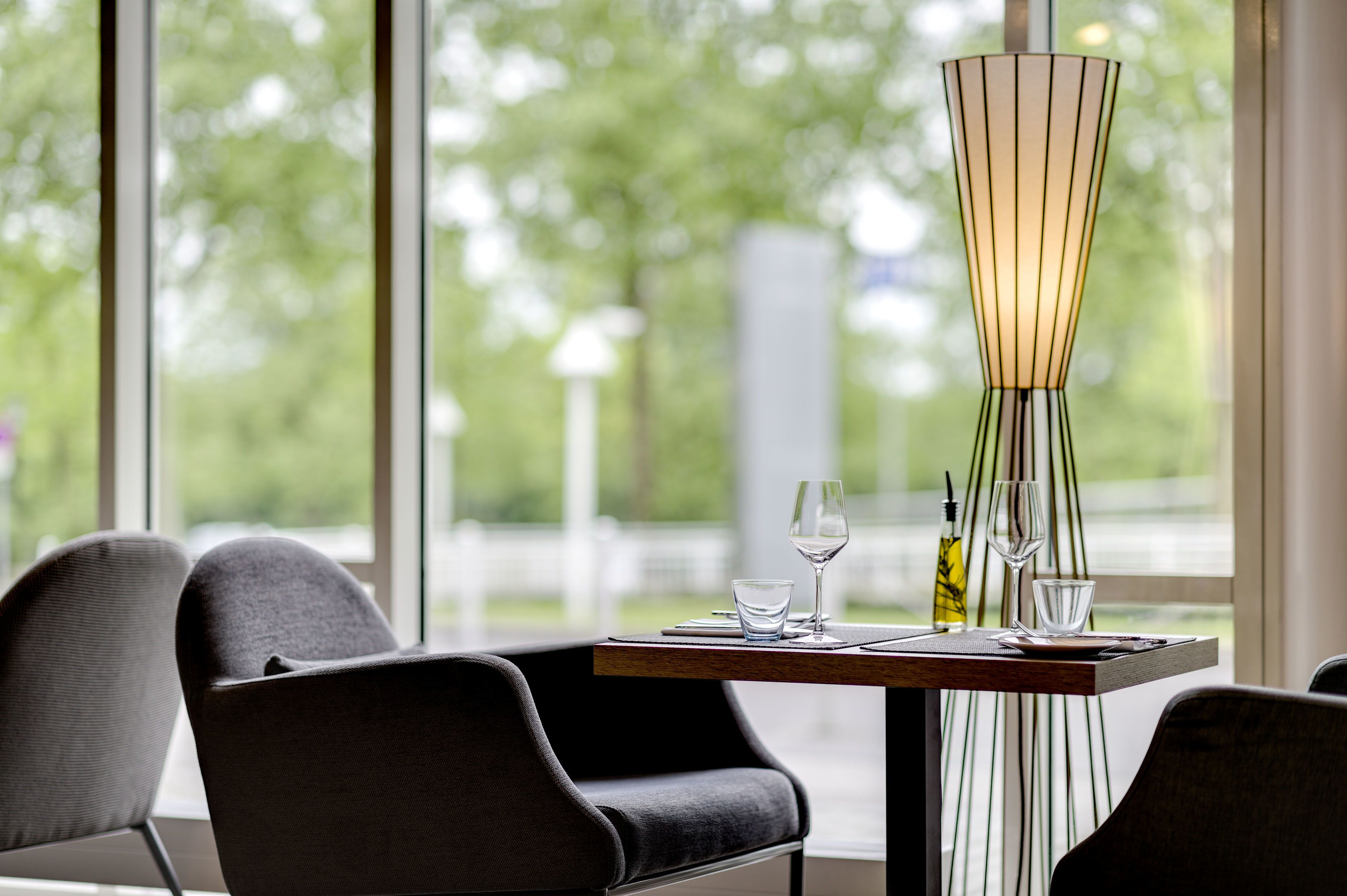 A dining area with a table set for two, featuring a modern lamp, wine glasses, and a bottle.