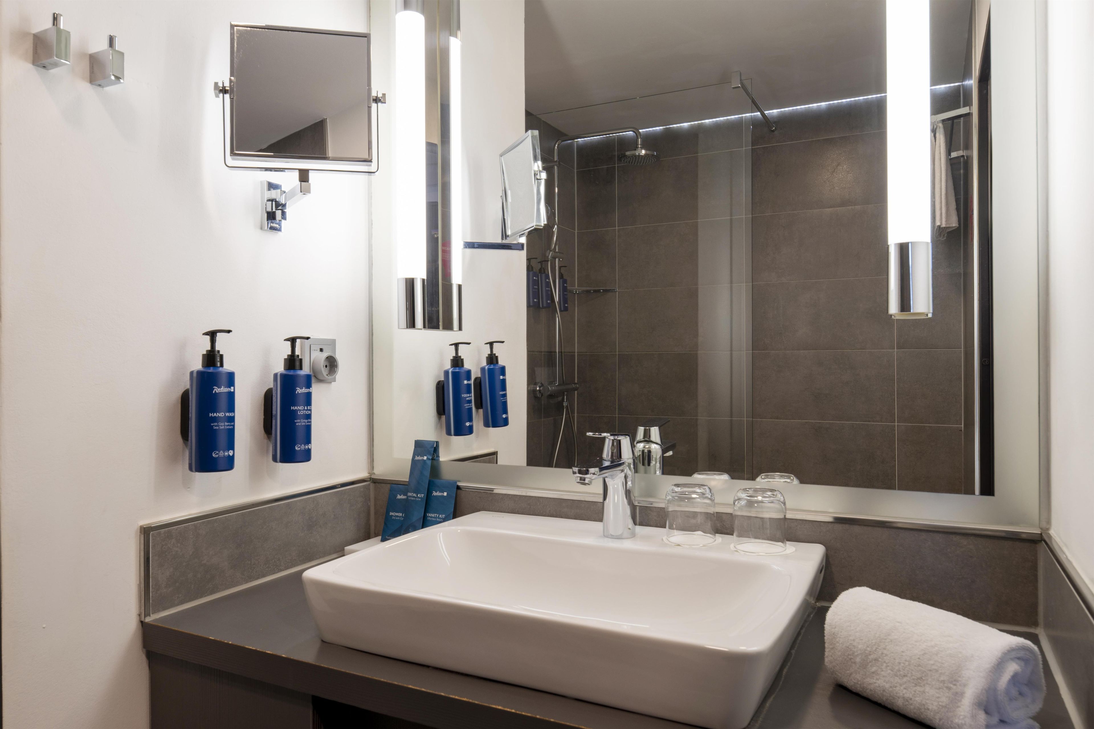 A modern bathroom with a large sink, a mirror, and a shower.
