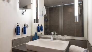 A modern bathroom with a large sink, a mirror, and a shower.