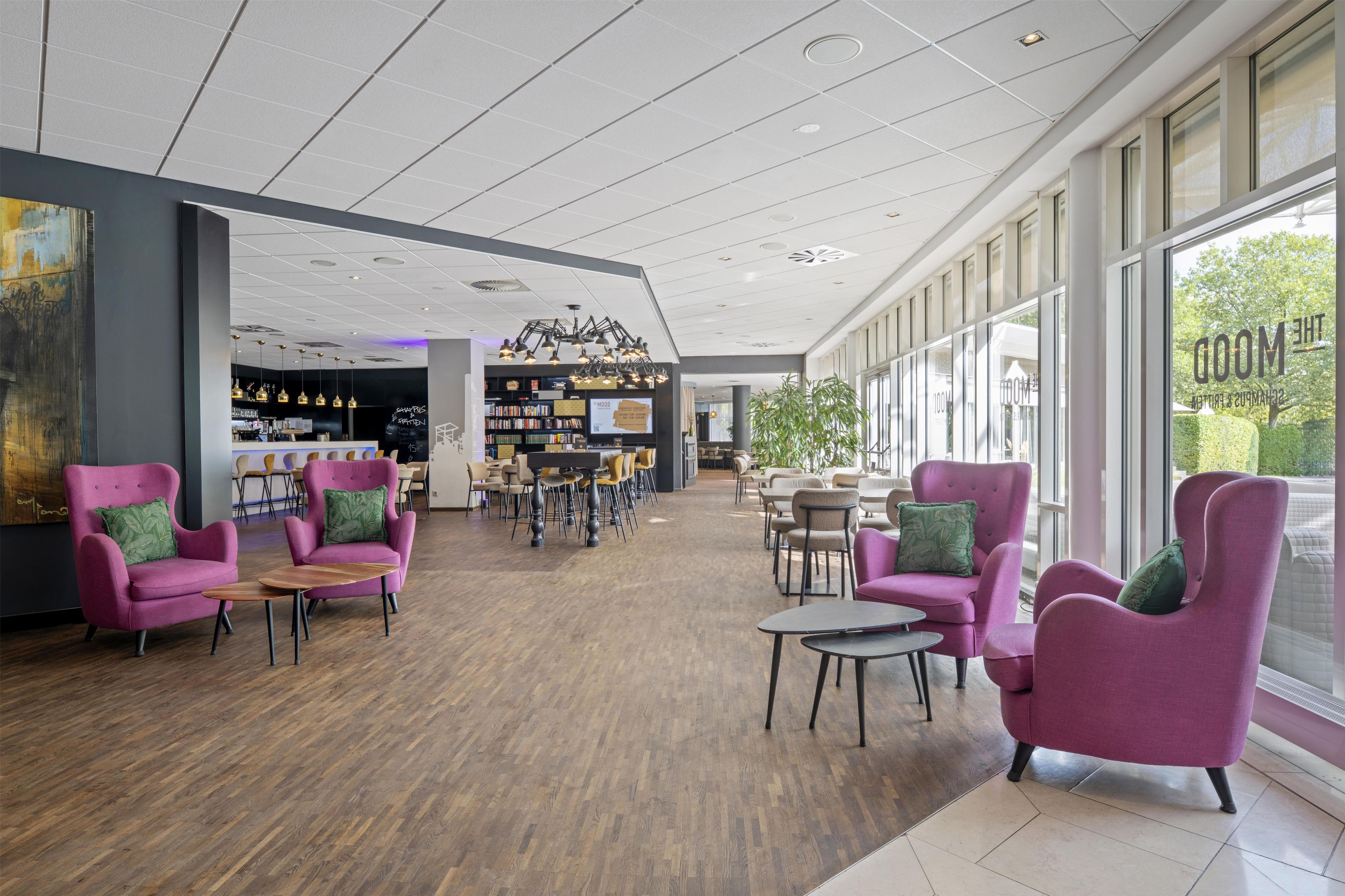 Eine geräumige Lobby mit Barbereich, Sitzgelegenheiten und großen Fenstern mit Ausblick.
