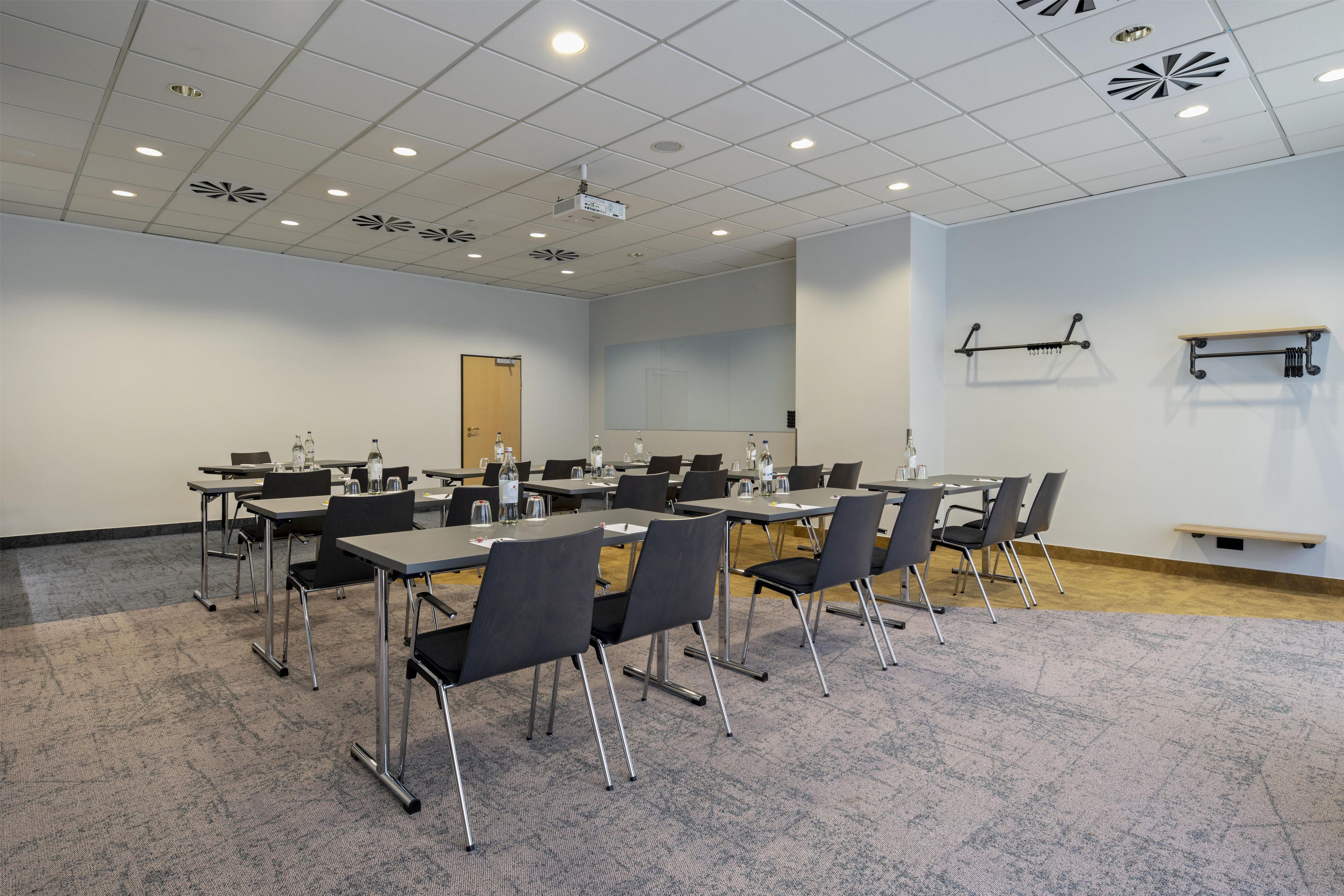 A conference room with tables and chairs, a projector, and a whiteboard.