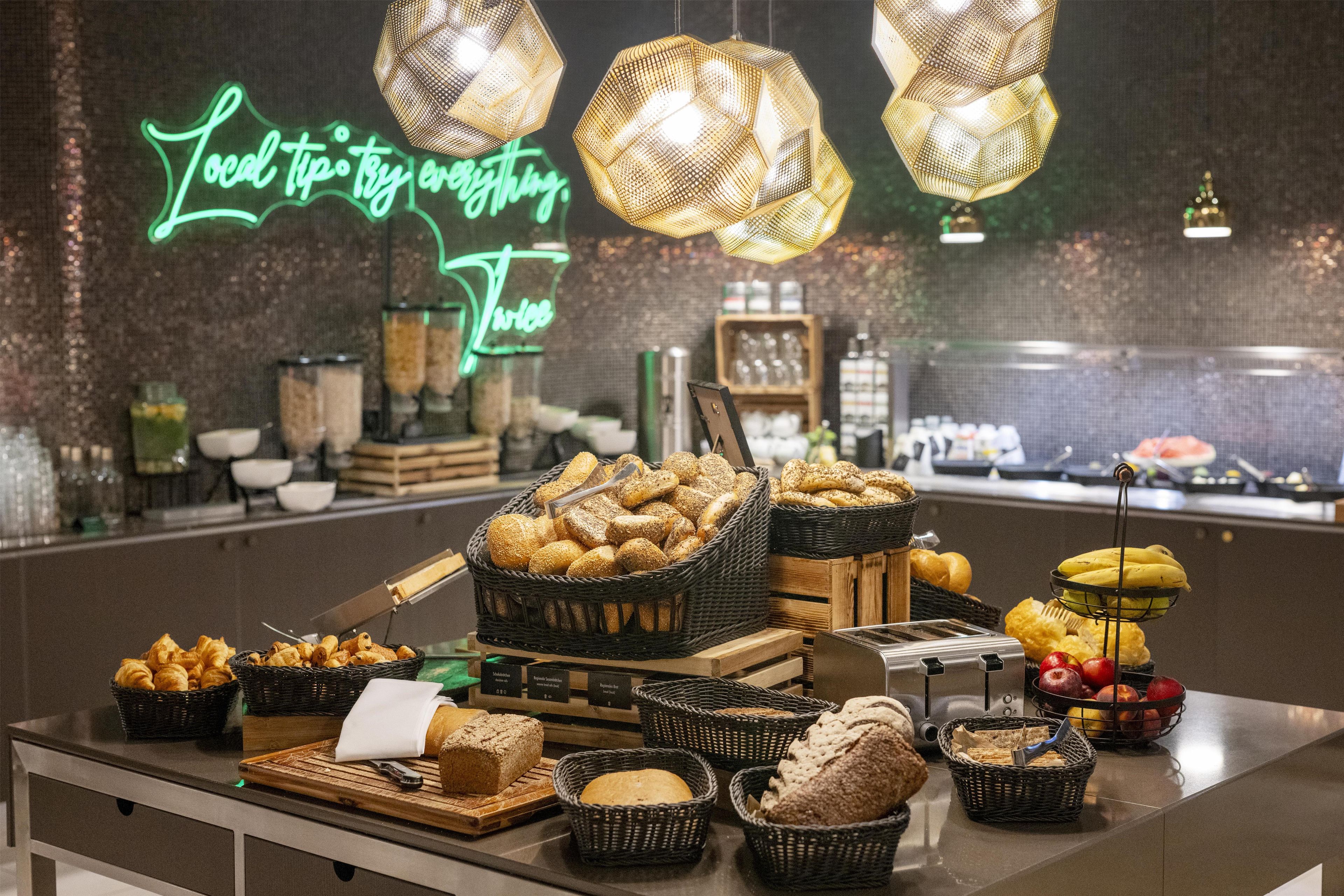 A buffet with various breads and pastries, a toaster, and a neon sign in the background.