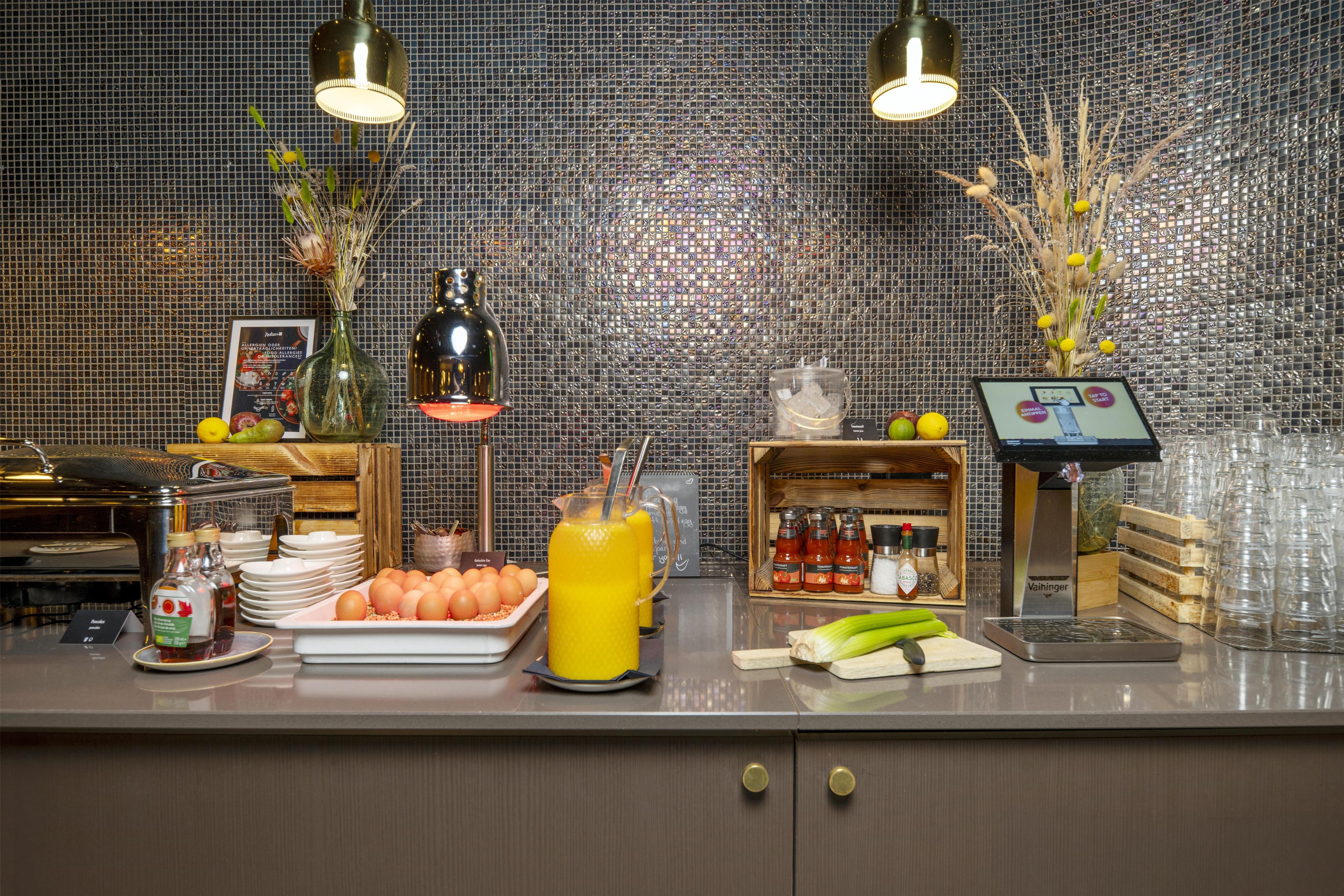 A breakfast buffet setup with various food items, a juice dispenser, and a beverage station.