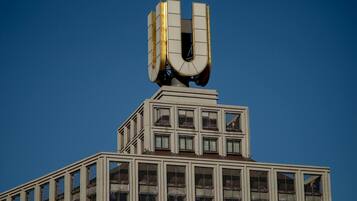 A building with a prominent U-shaped structure on top, large windows, and a clear blue sky in the background.