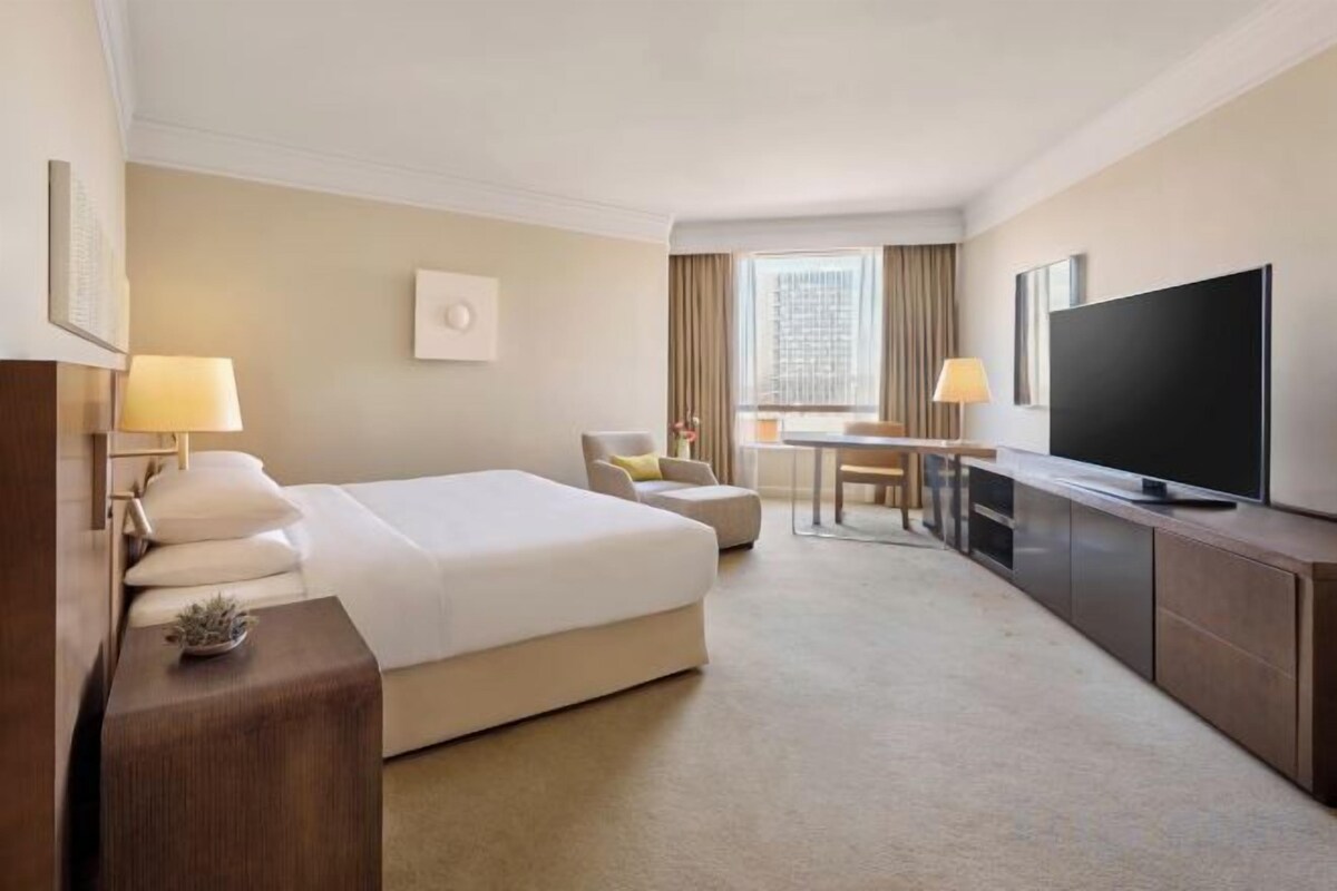 A hotel room with a bed, a TV, a desk, and a chair.