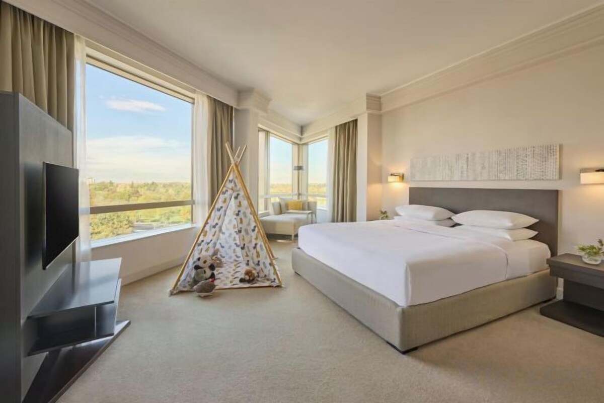 A hotel room with a large bed, a television, a teepee, and a balcony with a view.